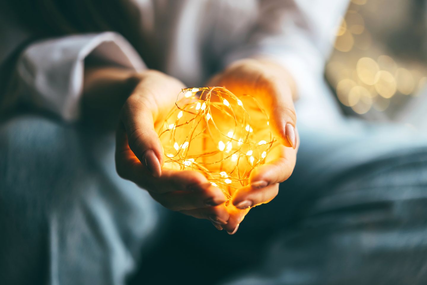 Hände halten eine gelb leuchtende Lichterkette. © Yana Iskayeva / Moment via Getty Images