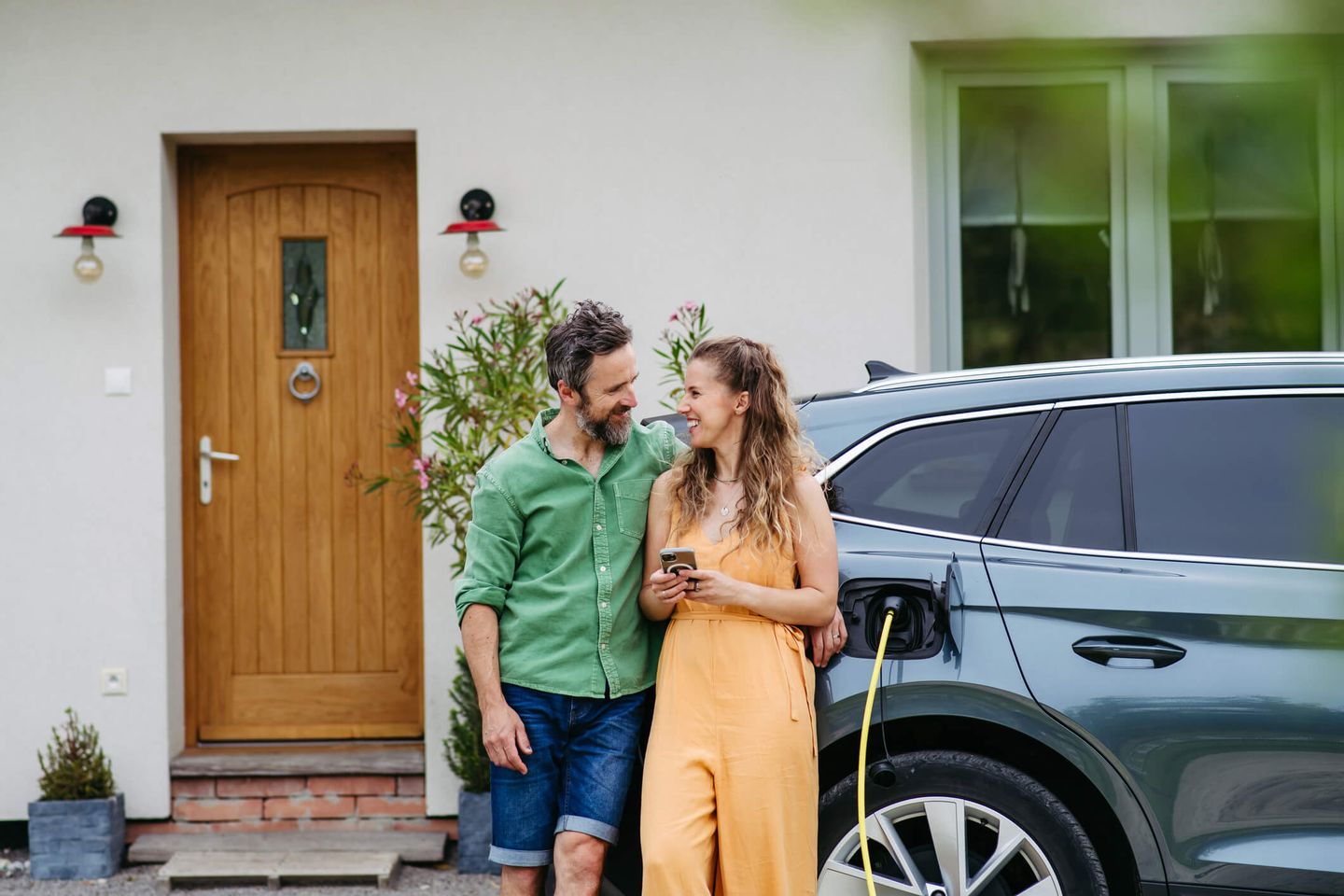 Ein junges Paar lädt sein E-Auto vor der eigenen Haustür. © Halfpoint Images via Getty Images