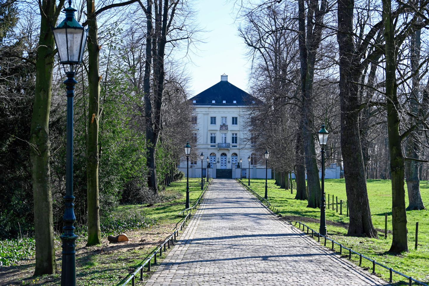 Das Schloss Mickeln mit Laternen und Bäumen, die die Zufahrt säumen. © We-Ge/ iStock Unreleased via Getty Images