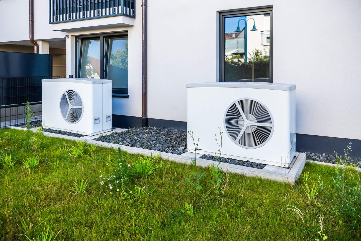 Zwei Wärmepumpen-Außengeräte vor einem modernen Wohnhaus. © rebca / iStock / Getty Images Plus via Getty Images © rebca / iStock / Getty Images Plus via Getty Images