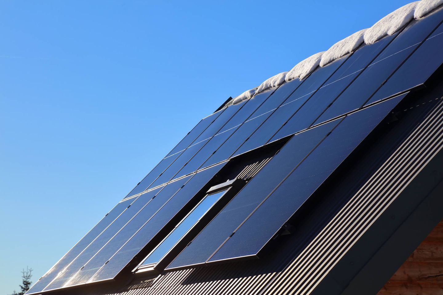 Eine PV-Anlage auf einem Dach, auf dessen First Schnee liegt. © tupungato / iStock / Getty Images Plus via Getty Images