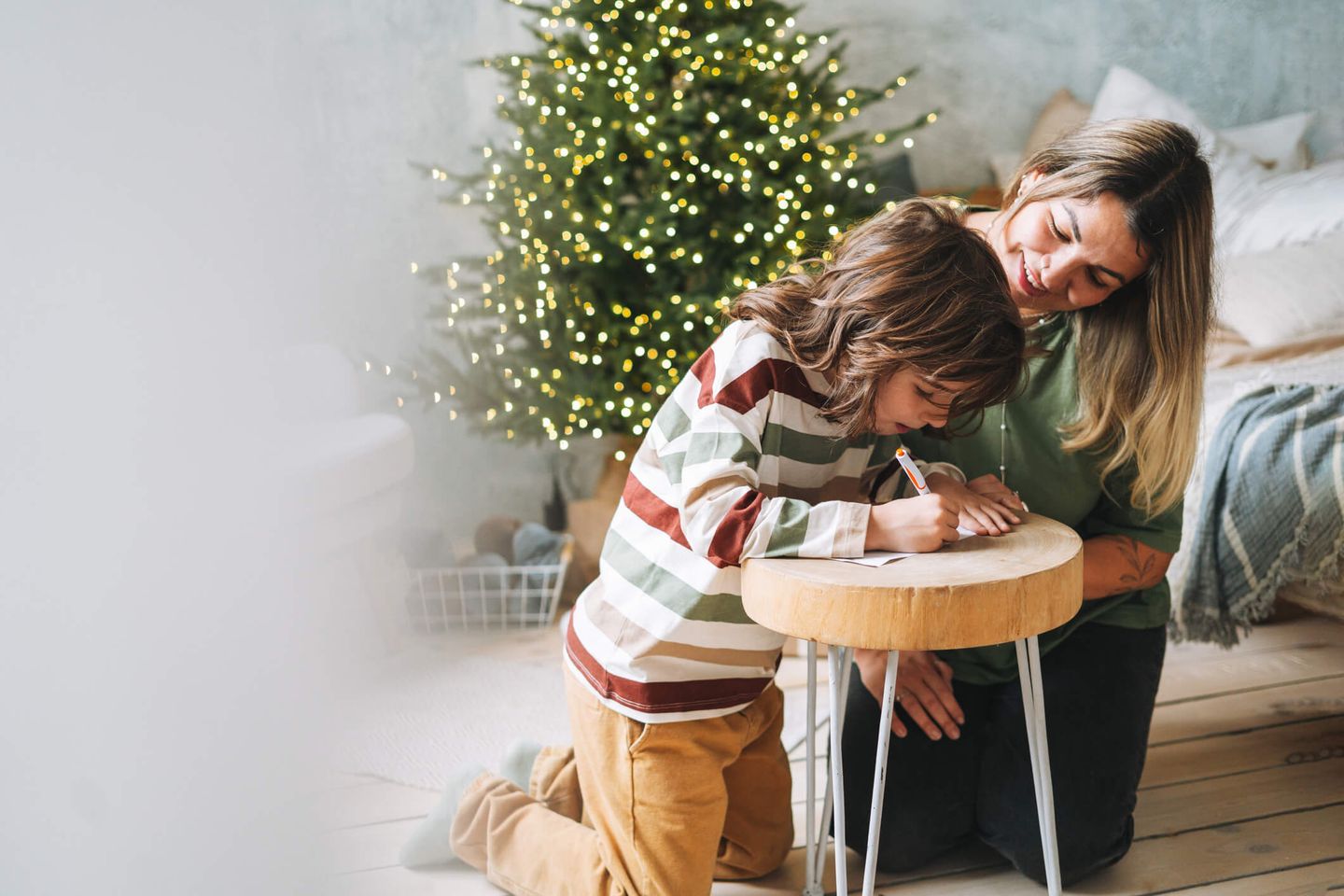 Eine Mutter und ihr Kind hocken auf dem Boden und schreiben einen Wunschzettel. © Galina Zhigalova / Moment via Getty Images © Galina Zhigalova / Moment via Getty Images