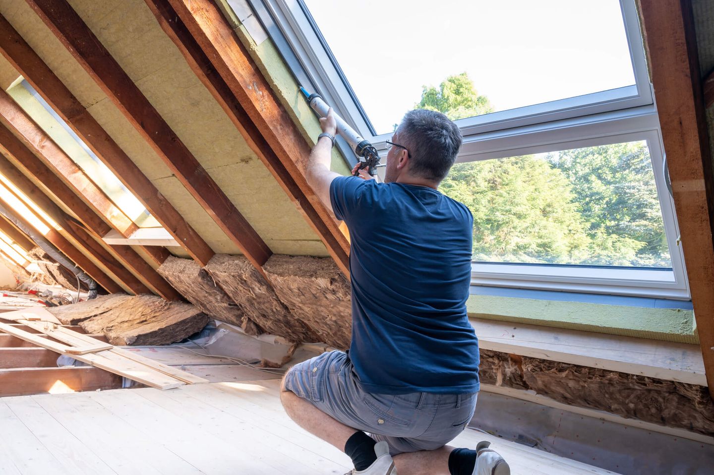 Ein Handwerker, der ein Fenster auf dem Dachboden abfässt.