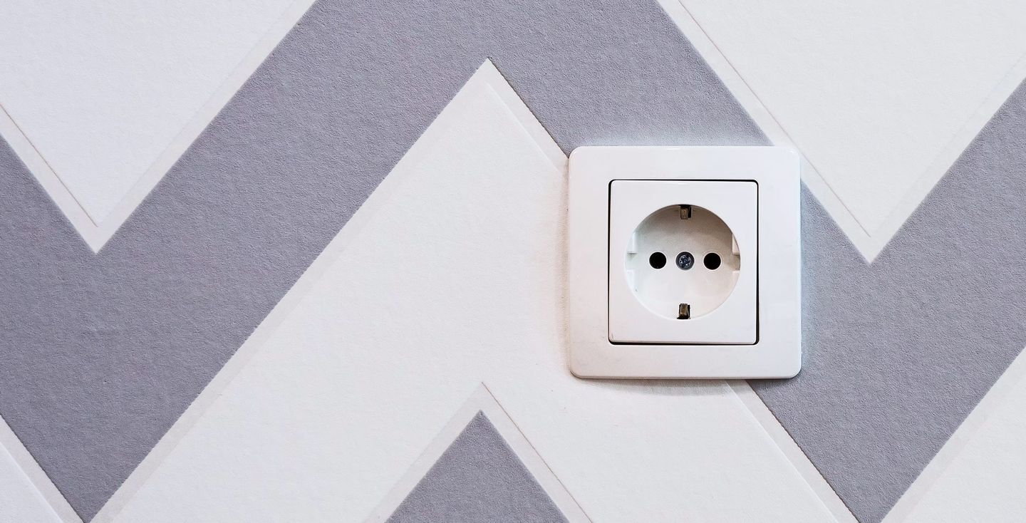 Steckdose an einer Wand mit grauen Muster Foto von Neven Krcmarek via https://unsplash.com/de/fotos/weisse-steckdosenleiste-montiert-auf-weiss-und-grau-chevron-lackierter-wand-67FG6zD8WPQ