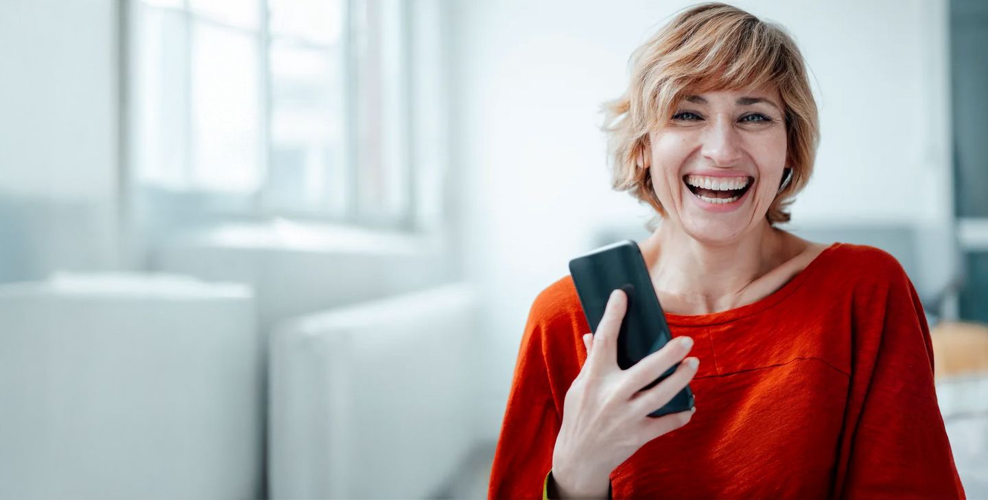 Eine lachende Frau mit einem Smartphone in der Hand. © Westend61 / via Getty Images © Westend61 via via Getty Images