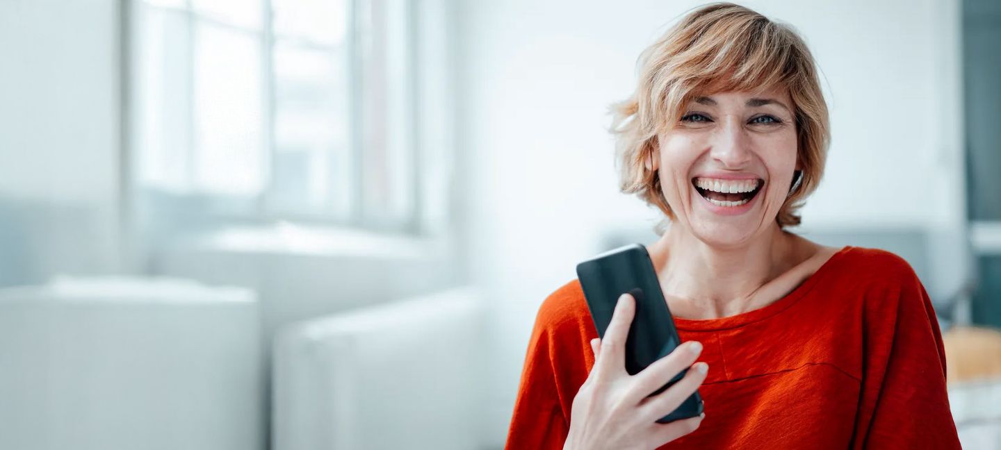 Eine lachende Frau mit einem Smartphone in der Hand. © Westend61 via via Getty Images