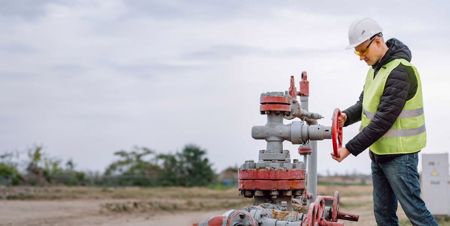 Ein Facharbeiter bedient die Leitungen für Gas und Öl auf einem Bohrplatz