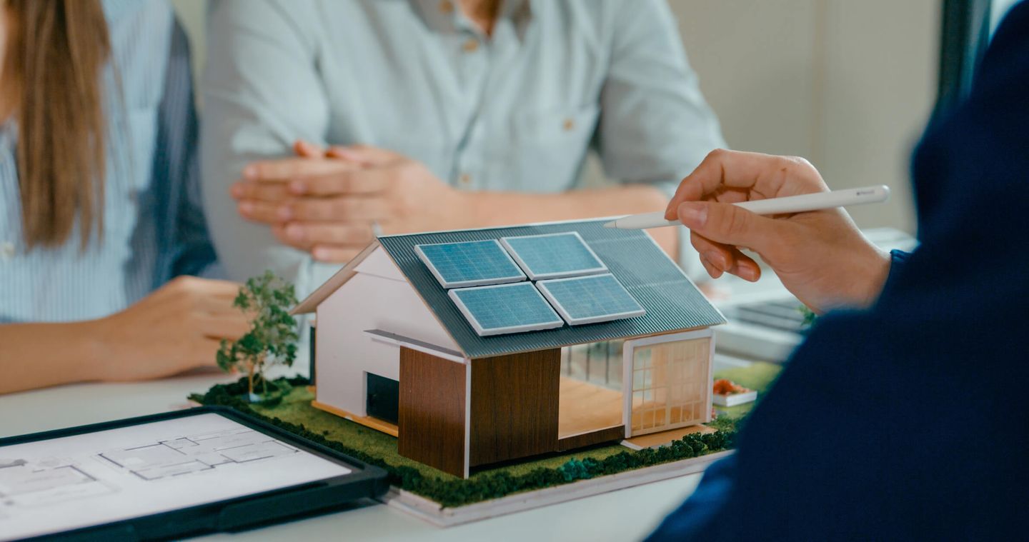Modellhaus mit Solaranlage bei einer Beratung zu nachhaltiger Energieversorgung. © MTStock Studio / E+ via Getty Images © MTStock Studio / E+ via Getty Images