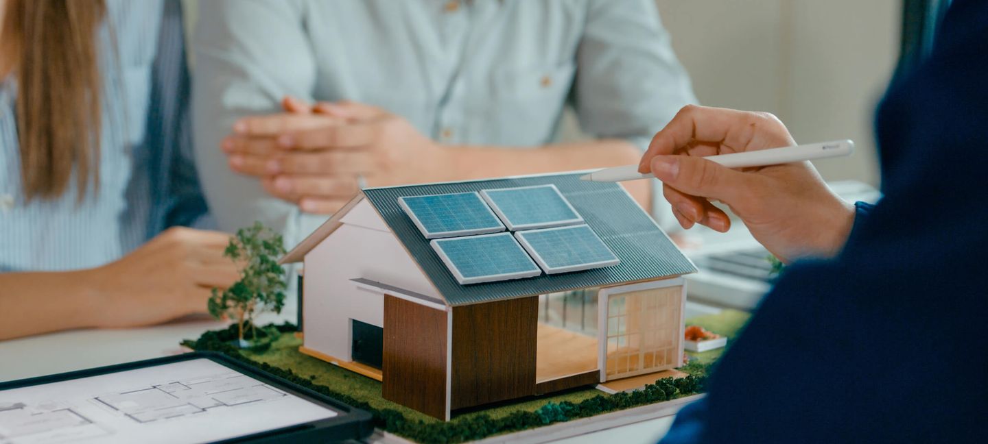 Modellhaus mit Solaranlage bei einer Beratung zu nachhaltiger Energieversorgung. © MTStock Studio / E+ via Getty Images