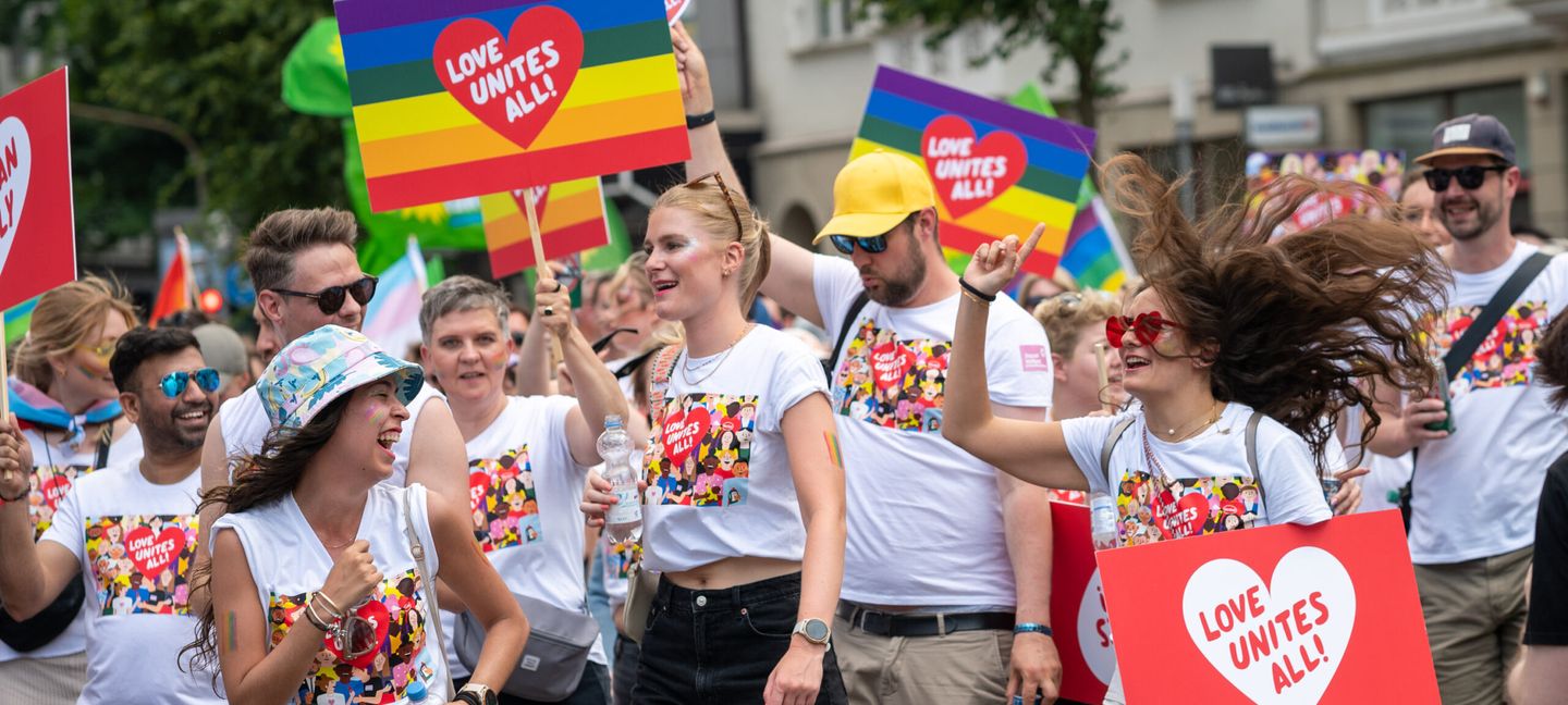 Feiernde mit bedruckten T-Shirts und Plakaten bei einer der vergangenen CSD Düsseldorf-Demonstrationen. © CSD Düsseldorf e. V. © CSD Düsseldorf e. V.