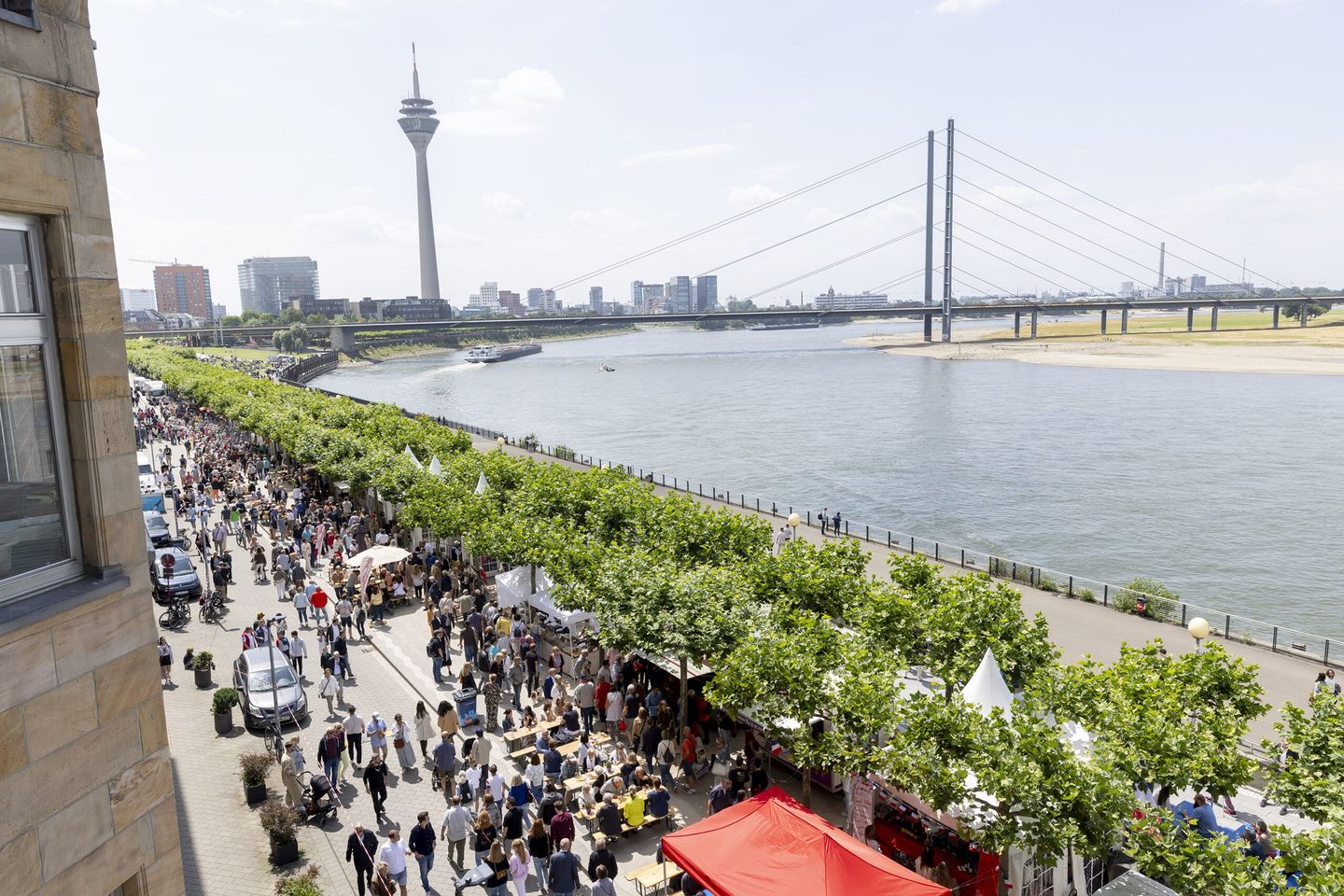 Die gut besuchte Rheinuferpromenade Düsseldorf im Vorder- und der Rheinturm im Hintergrund.  © Destination Düsseldorf Veranstaltungs GmbH / Wellfairs GmbH via www.duesseldorfer-frankreich-fest.de