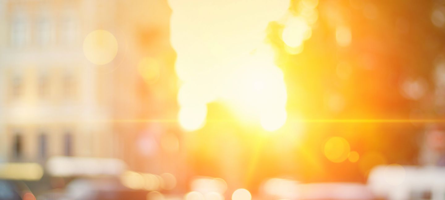 Tief stehende Sonne zwischen Gebäuden und Fahrzeugen in einer dicht bebauten Stadt © inspired_by_the_light via Getty Images