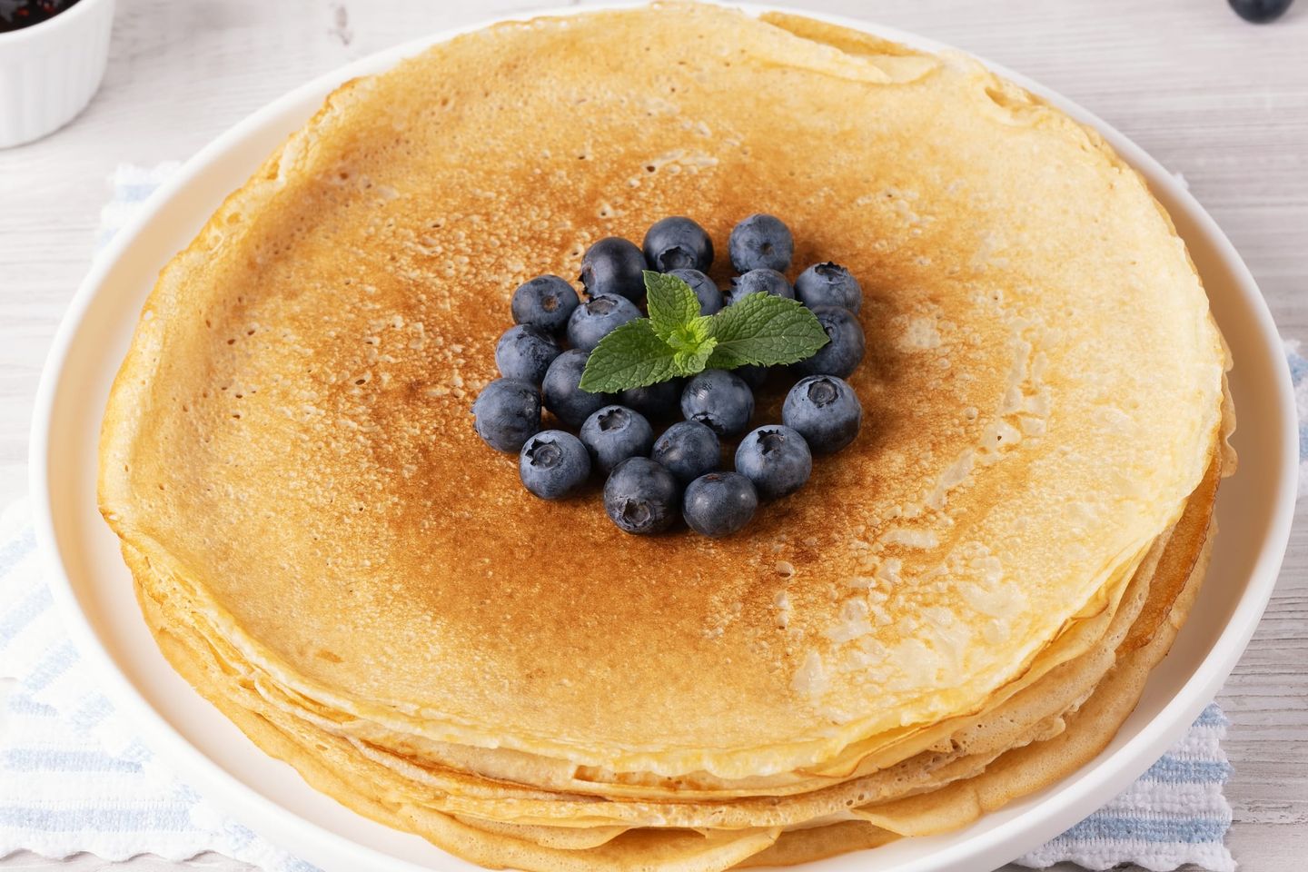 Frischer Stapel goldbrauner veganer Pfannkuchen, garniert mit Heidelbeeren und einem Zweig frischer Minze in der Mitte