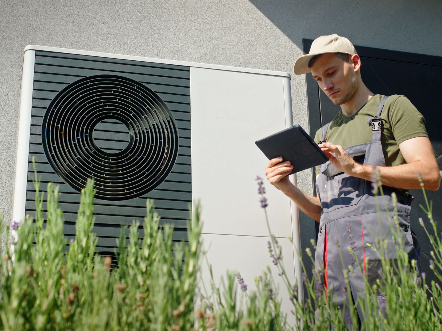 Techniker mit Tablet bei der Inspektion einer modernen Wärmepumpe. © StockSeller_ukr / iStock / Getty Images Plus via Getty Images