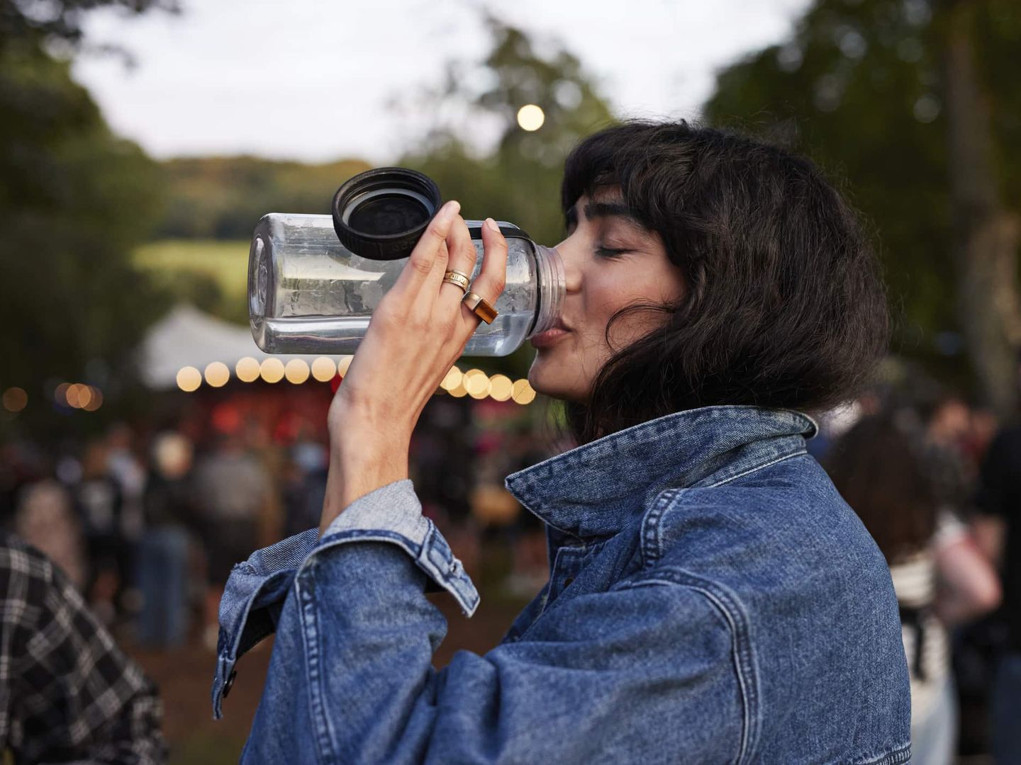Eine Frau trinkt Wasser aus einer wiederverwendbaren Flasche auf einem Festival. Getty