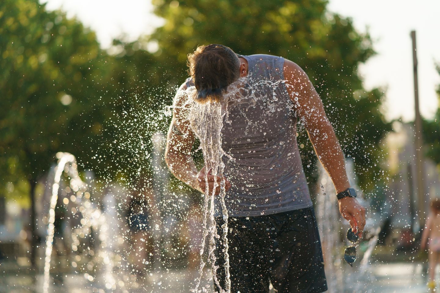 Mann kühlt sich bei großer Sommerhitze an einem öffentlichen Wasserspiel ab © Yury Karamanenko via Getty Images