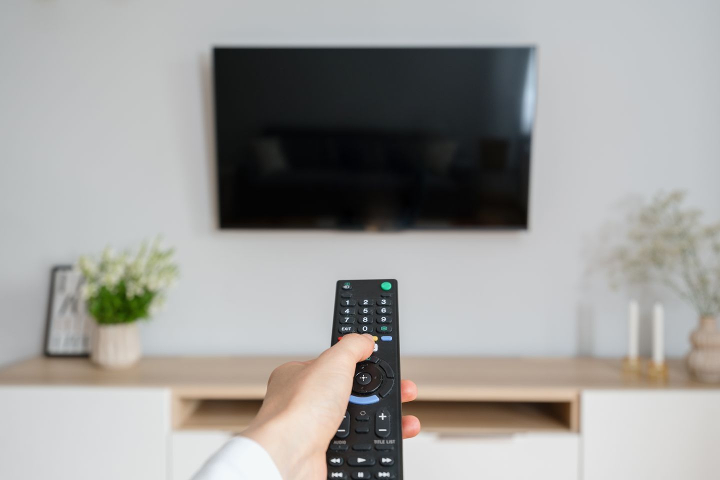 Person schaltet einen Fernseher im Standby-Modus mit einer Fernbedienung ein brizmaker via Getty Images