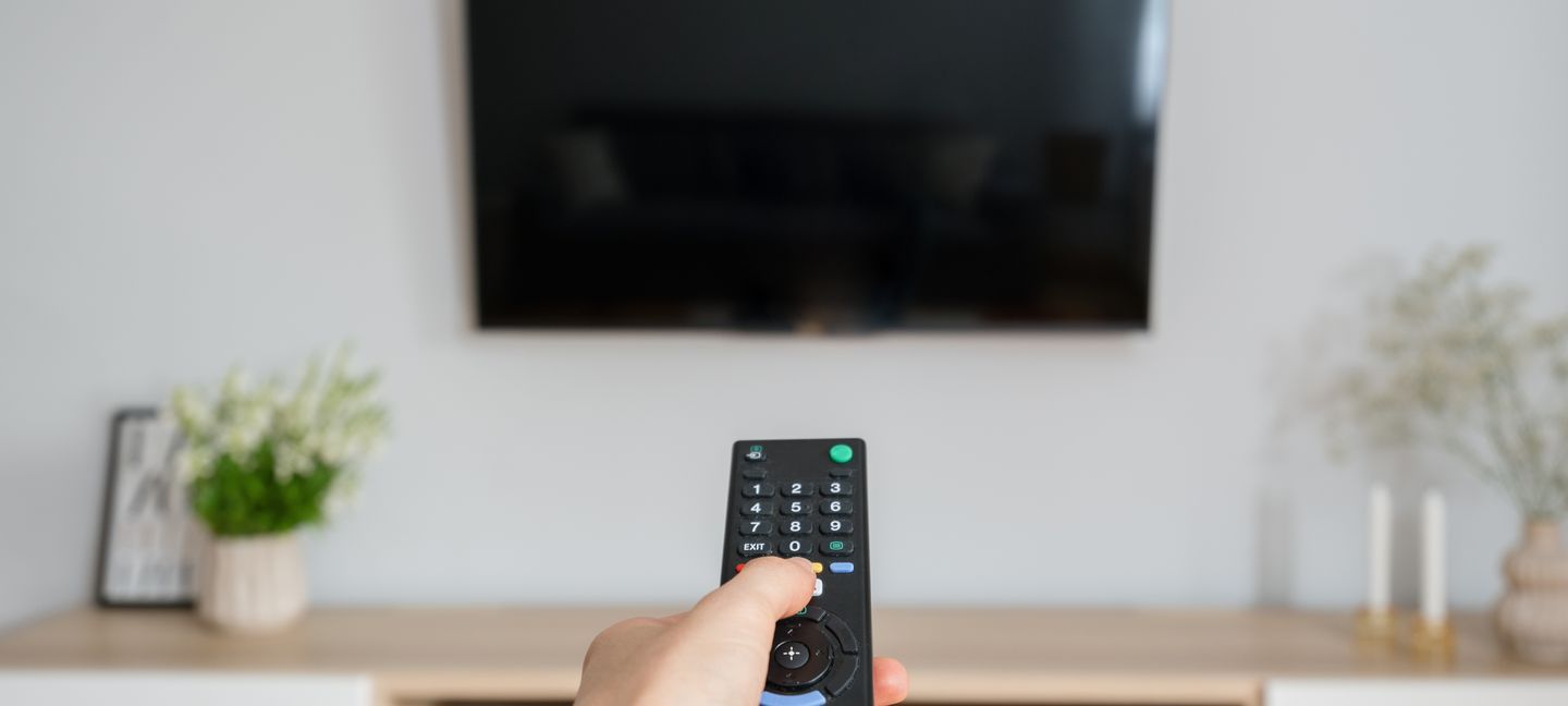 Person schaltet einen Fernseher im Standby-Modus mit einer Fernbedienung ein brizmaker via Getty Images