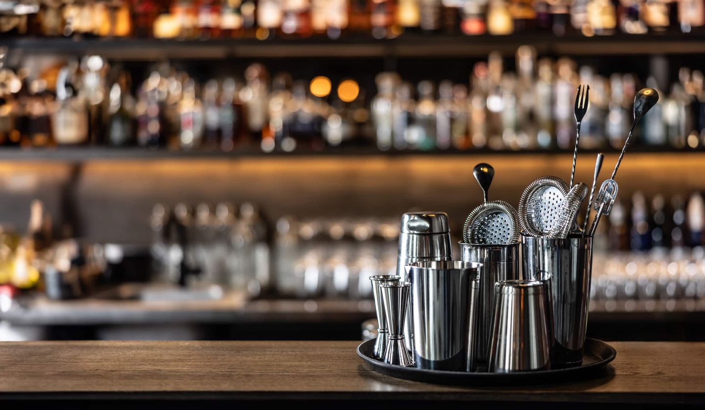 Cocktail-Utensilien wie Shaker, Barsieb und Messbecher stehen ordentlich auf einer Bar bereit. Getty