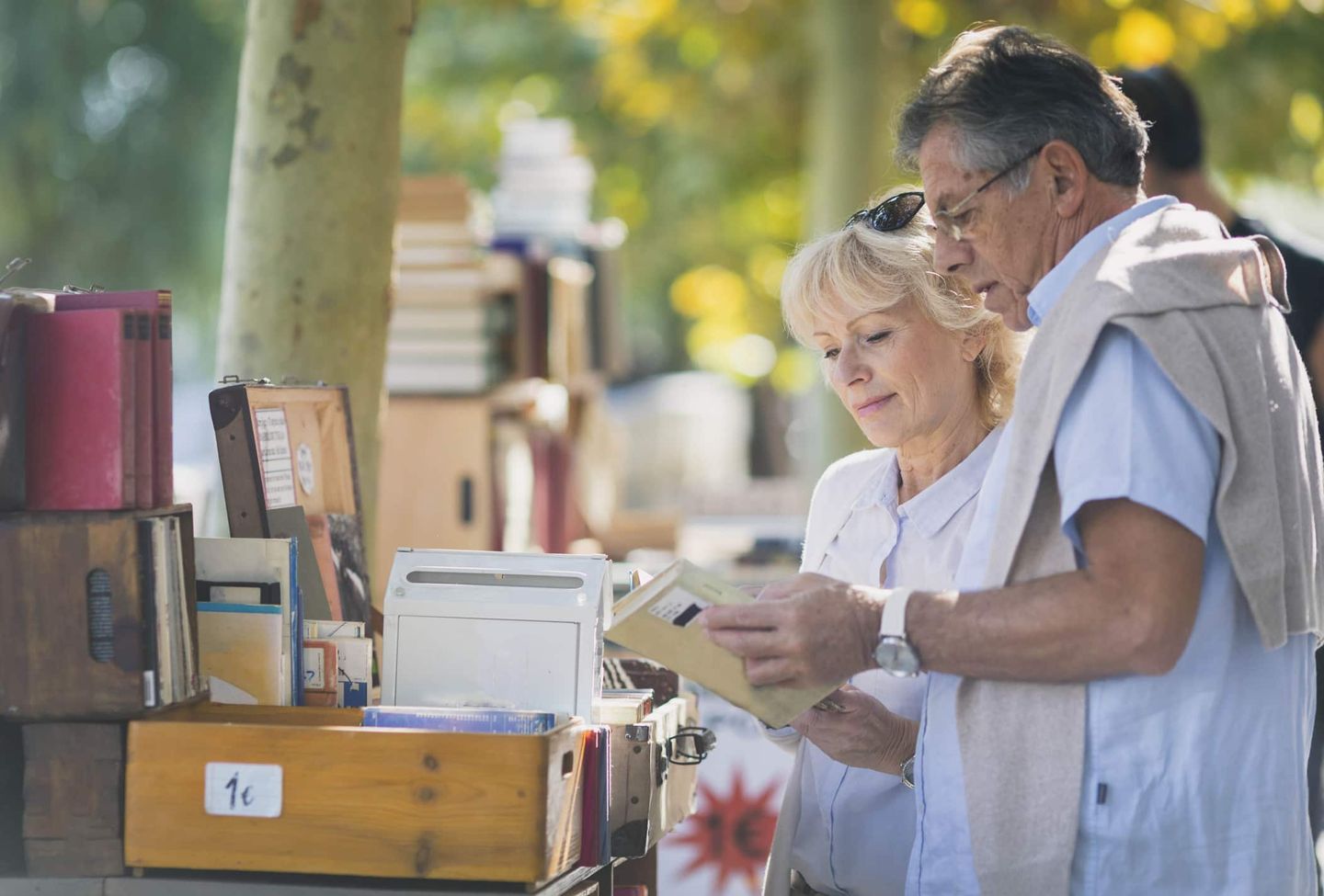 Älteres Paar stöbert auf einem Flohmarkt in alten Büchern. Getty