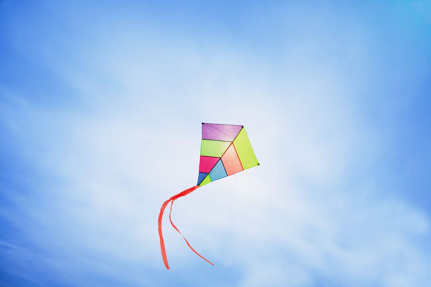 Ein bunter Drachen fliegt hoch am Himmel vor blauem Hintergrund. Getty