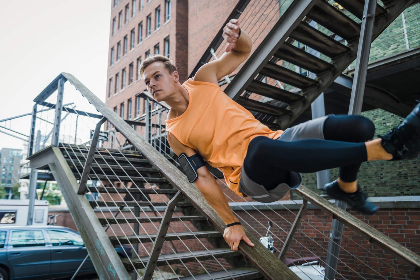 Athlet in orangem Shirt überwindet ein Geländer beim Parkour-Training. Getty