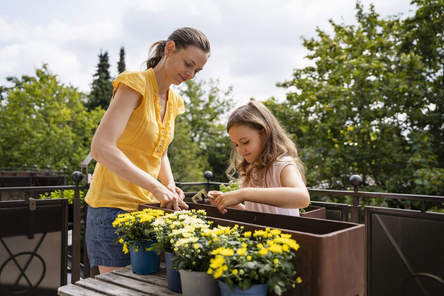 Mutter und Tochter bepflanzen Blumenkästen auf dem Balkon Getty