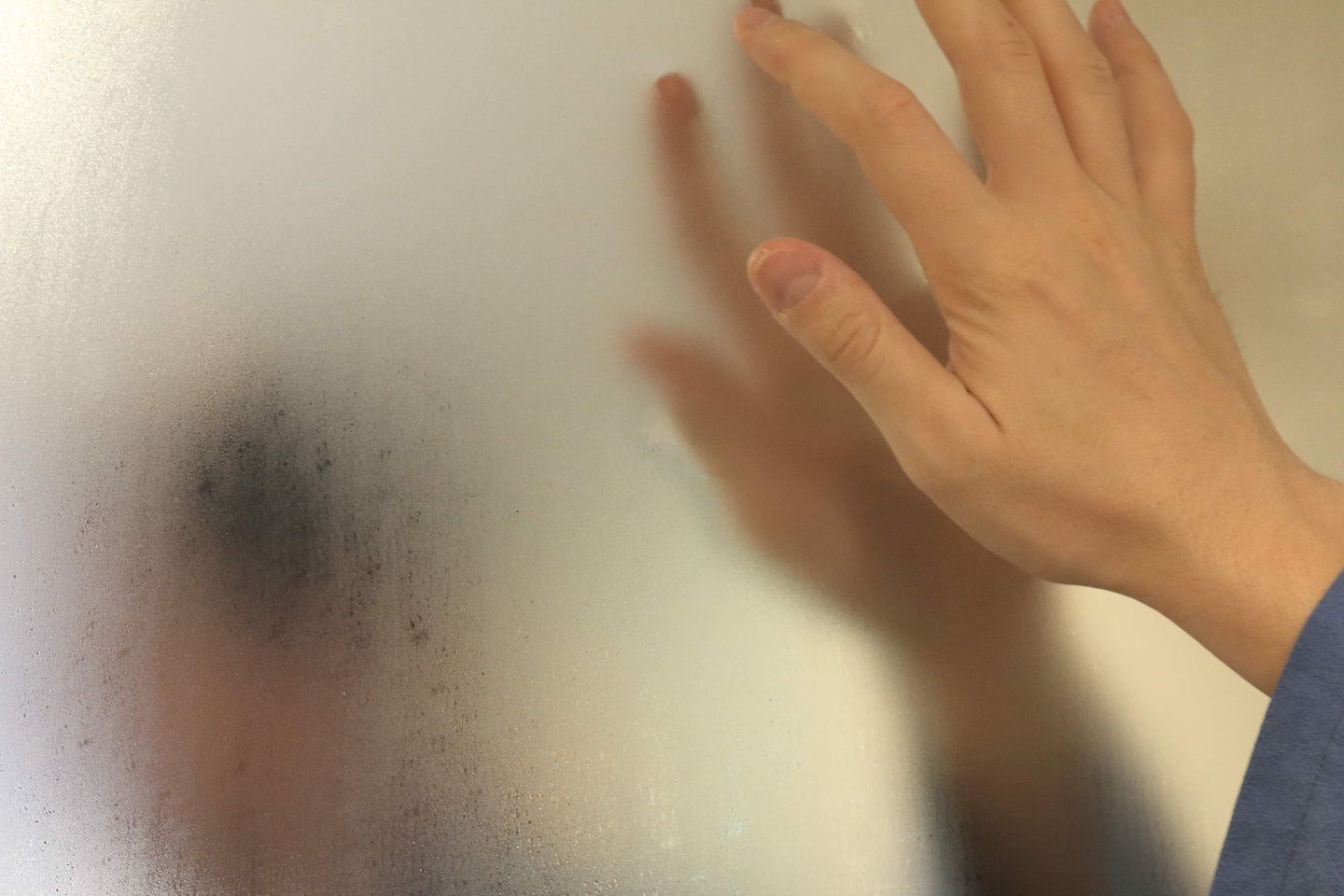 Hand berührt eine beschlagene Glasscheibe. Getty
