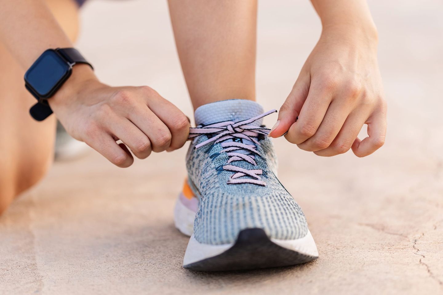 Nahaufnahme einer Person, die sich die Sportschuhe zum Joggen schnürt.