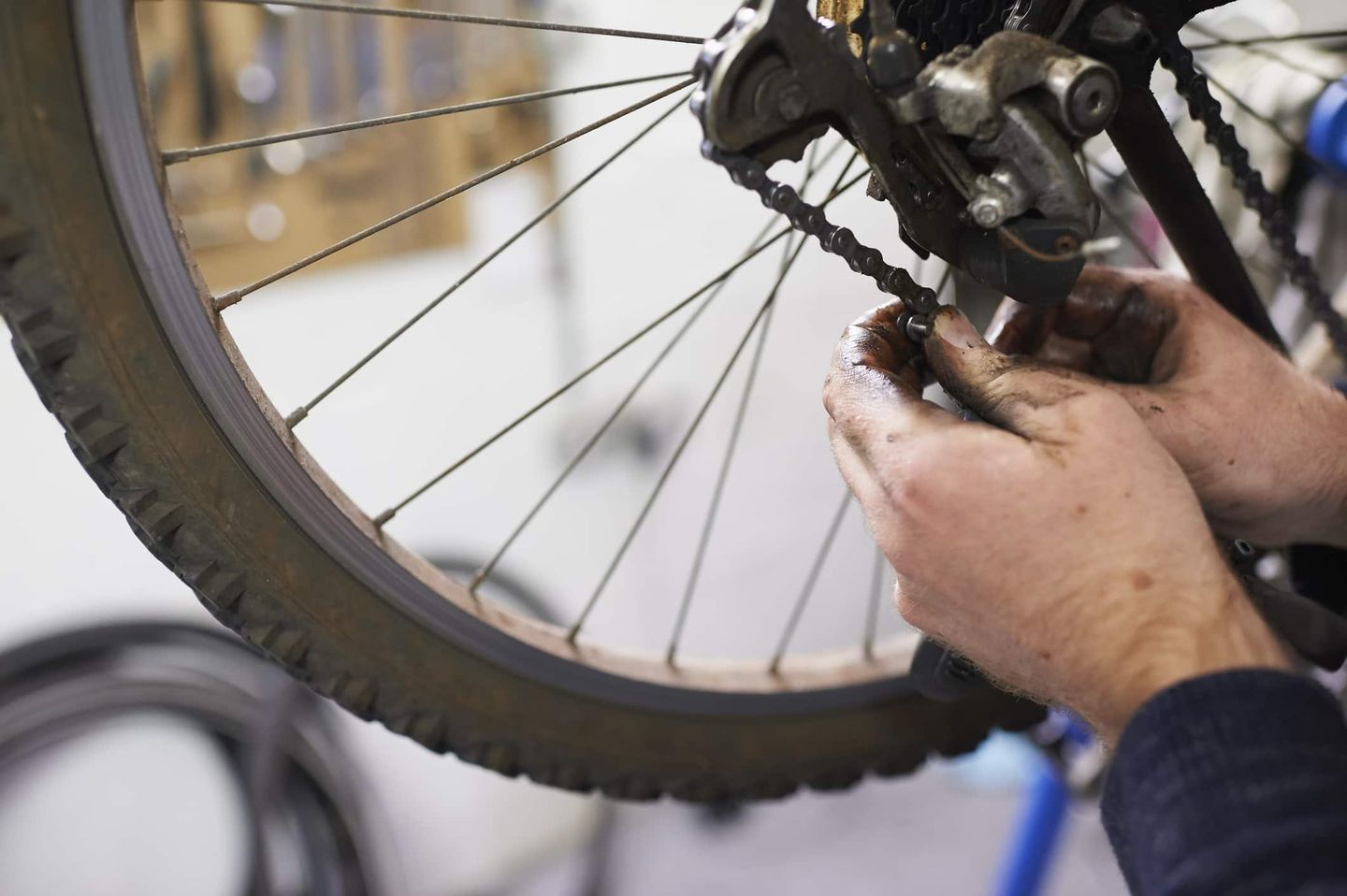 Nahaufnahme einer Person mit schmutzigen Händen, die eine Fahrradkette repariert. Getty