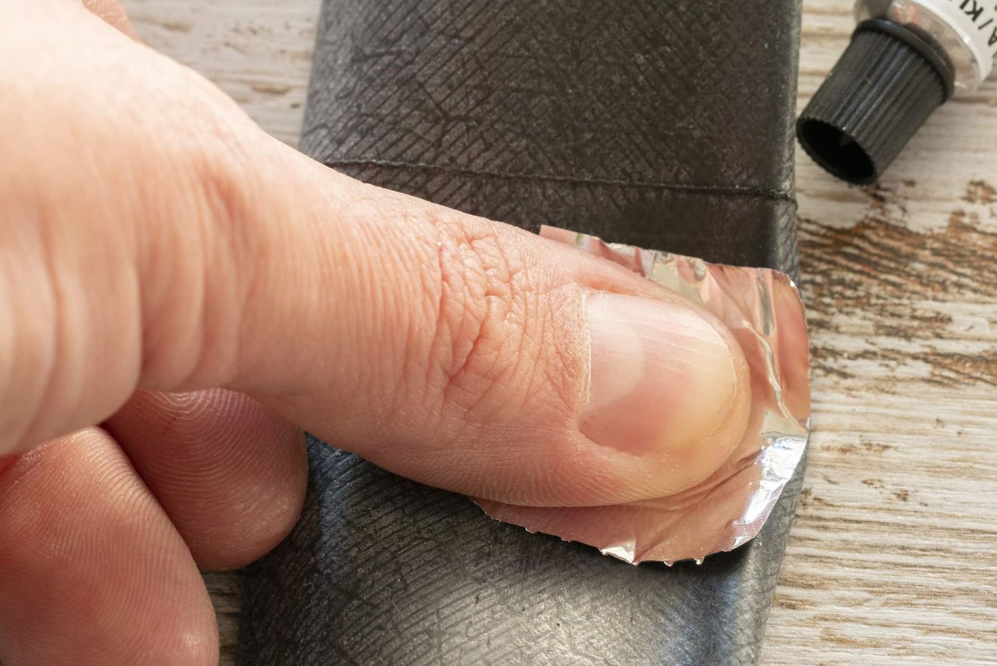 Finger drückt ein Stück Aluminiumfolie auf ein Fahrradteil, wahrscheinlich zum temporären Abdichten oder Reparieren Getty