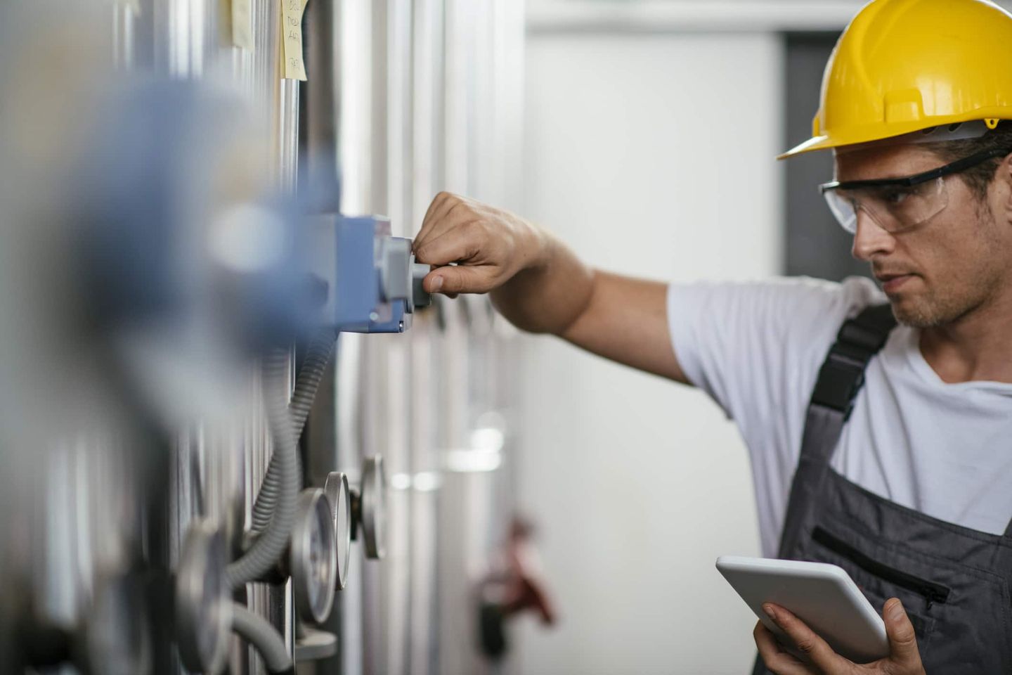 Handwerker mit Schutzhelm arbeitet an Heizungsanlage mit Tablet. Getty