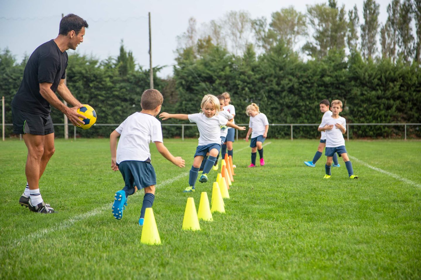 Ein Fußballtrainer betreut eine Gruppe Kinder beim Training auf dem Sportplatz. Getty