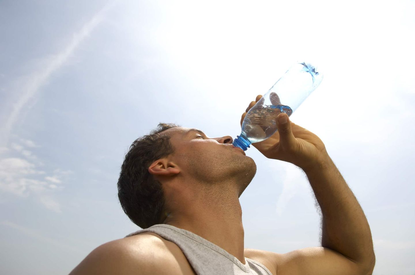 Mann trinkt im Freien Wasser aus einer Plastikflasche. Getty