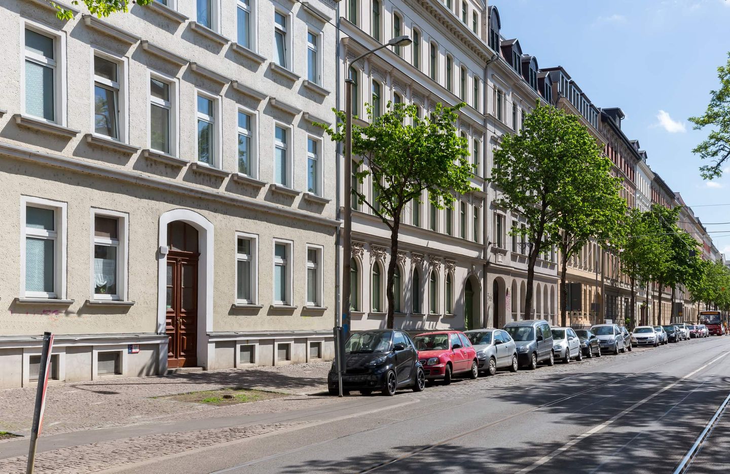 Reihe von Altbauten mit parkenden Autos an einer sonnigen Straße. Getty