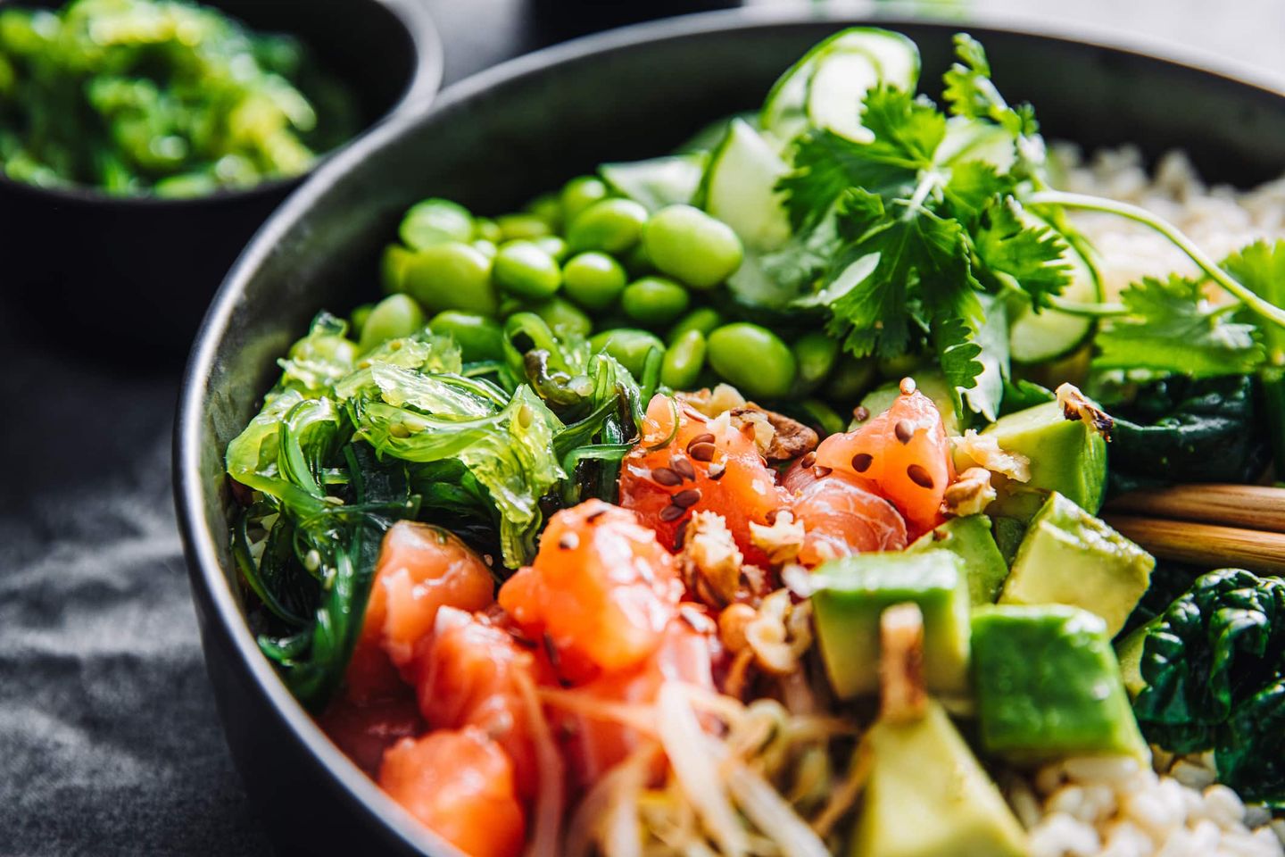 Nahaufnahme einer bunten Poké Bowl mit Lachs, Avocado, Edamame und Algen. Getty