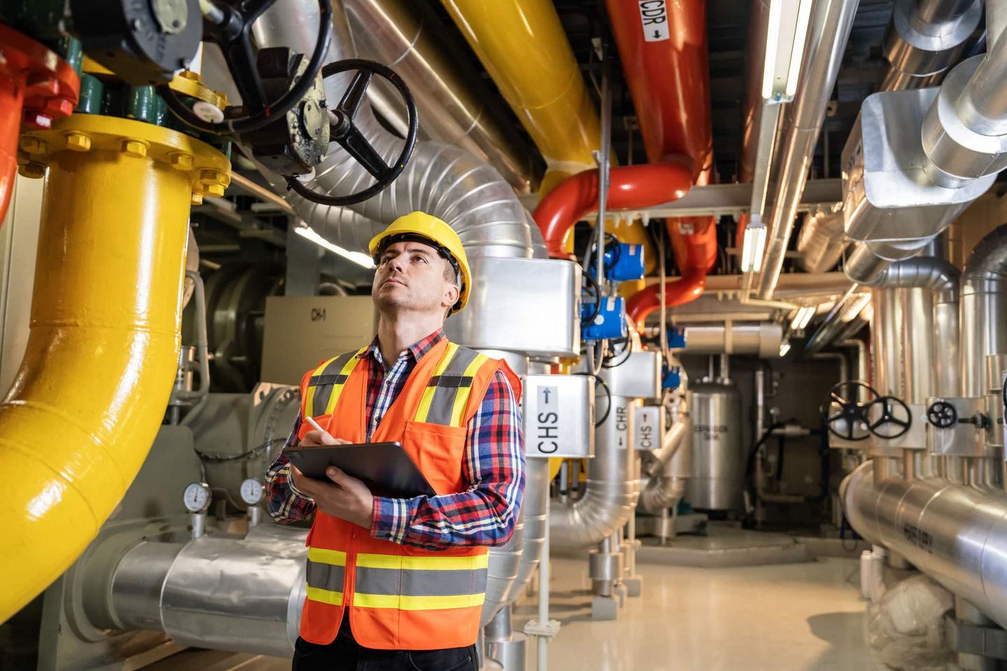 Techniker in Schutzkleidung überprüft Rohre und Ventile in einer Schwimmbadtechnik-Anlage Getty