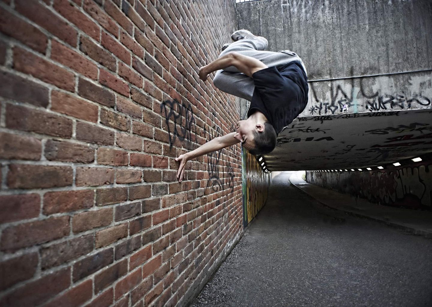 Sportler macht einen Rückwärtssalto an einer Backsteinwand in einem Tunnel. Getty