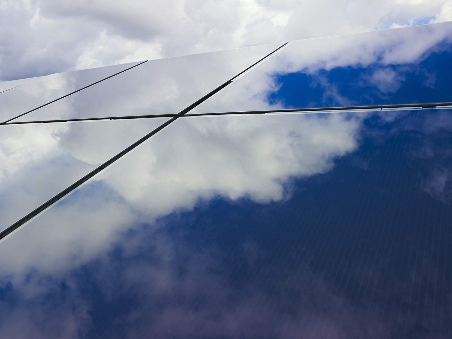 Nahaufnahme von glänzenden Solarpaneelen mit Wolkenreflexion. Getty