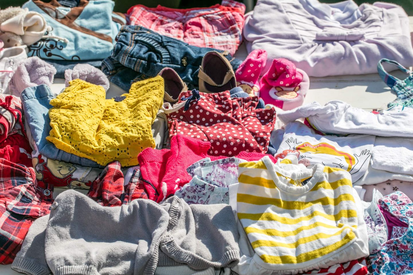 Bunte Kinderkleidung und Schuhe auf einem Flohmarktstand ausgebreitet. Getty