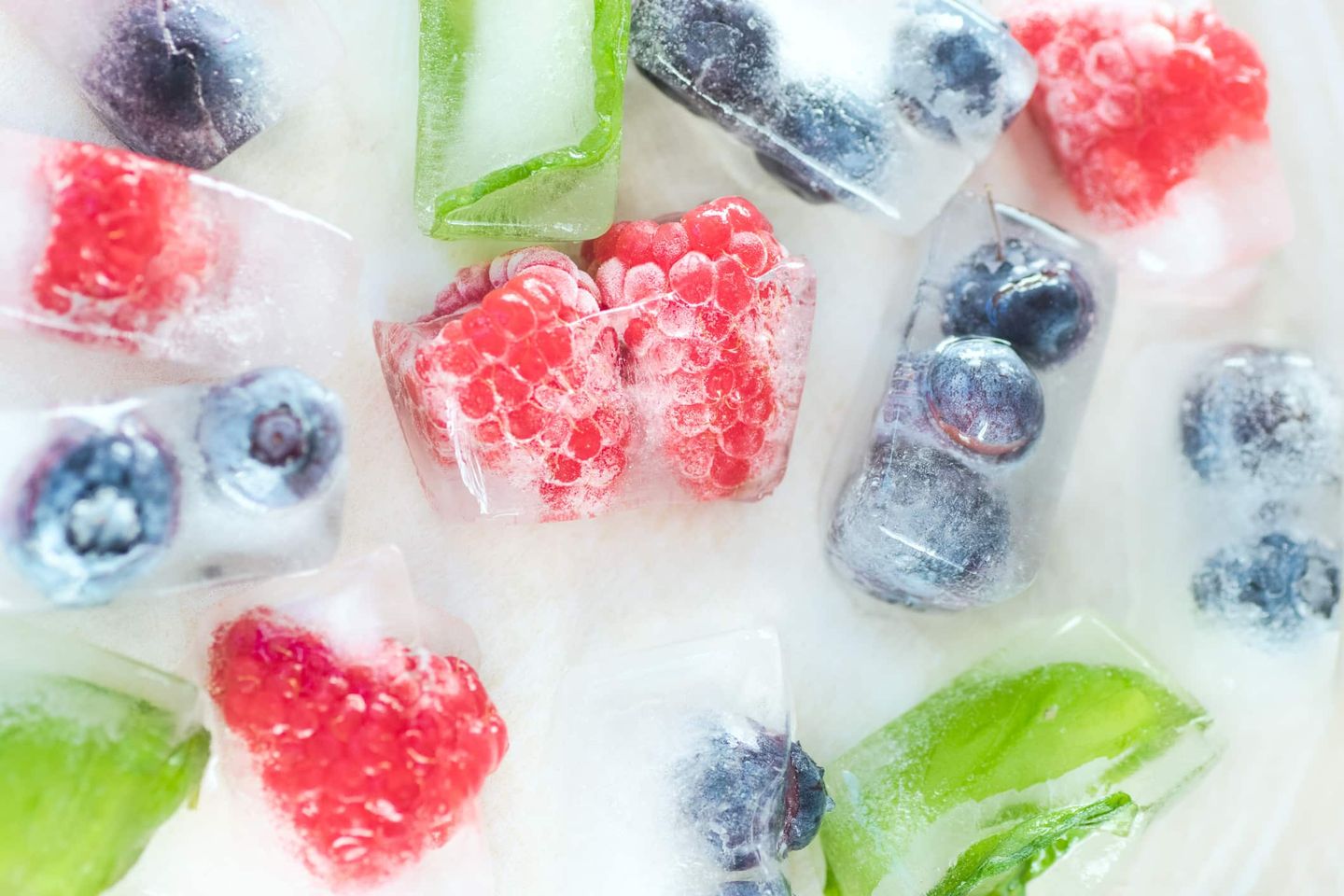 Ganze Himbeeren und Blaubeeren in gefrorenen Eiswürfeln. Getty