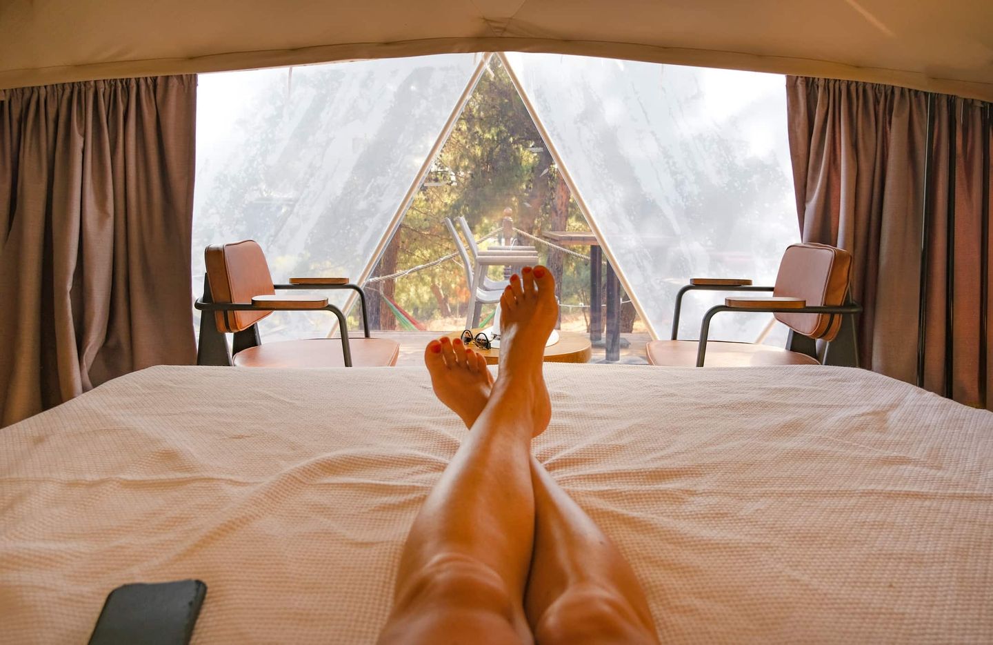 Blick aus einem Glamping-Zelt auf Terrasse mit Stühlen Getty