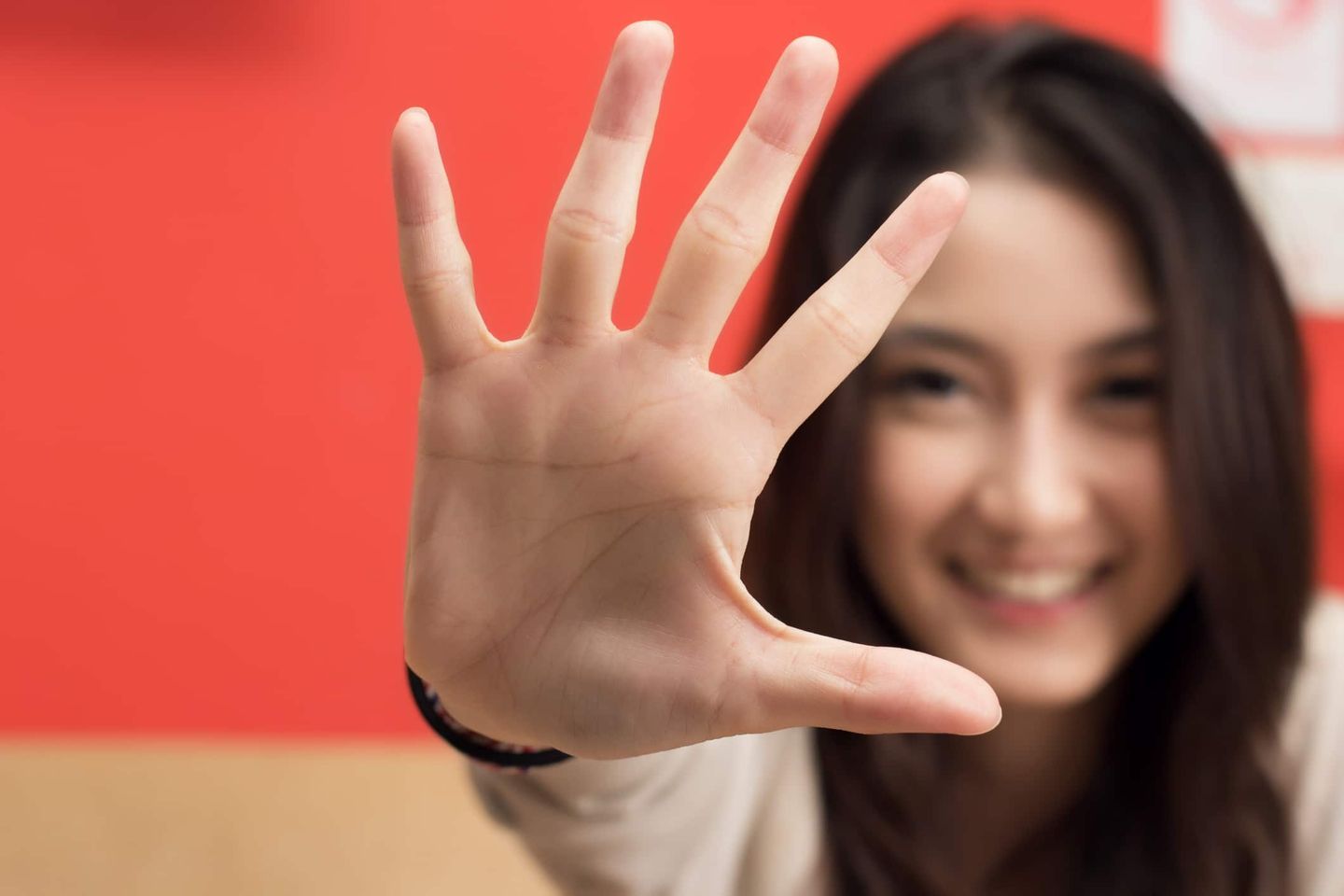 Junge Frau hält ihre Hand mit gespreizten Fingern in die Kamera. Getty