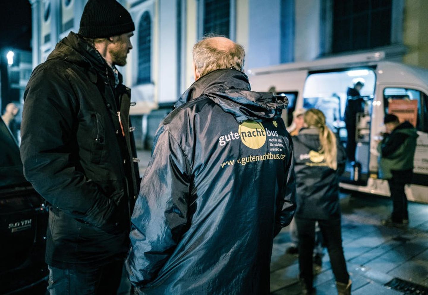 Zwei Helfer stehen vor dem gutenachtbus in Düsseldorf und unterhalten sich.