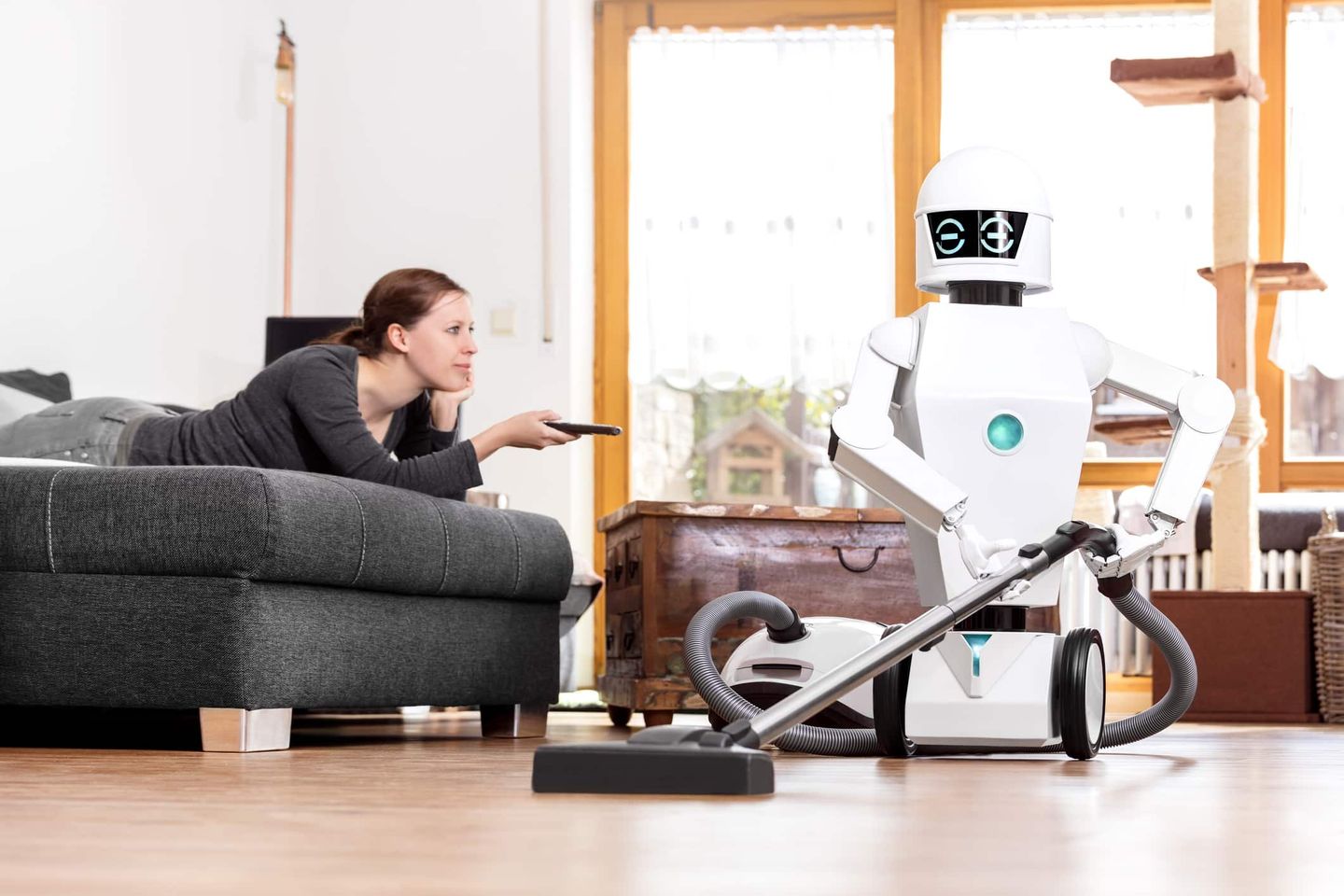 Frau beobachtet, wie ein humanoider Roboter mit Staubsauger den Boden reinigt Getty