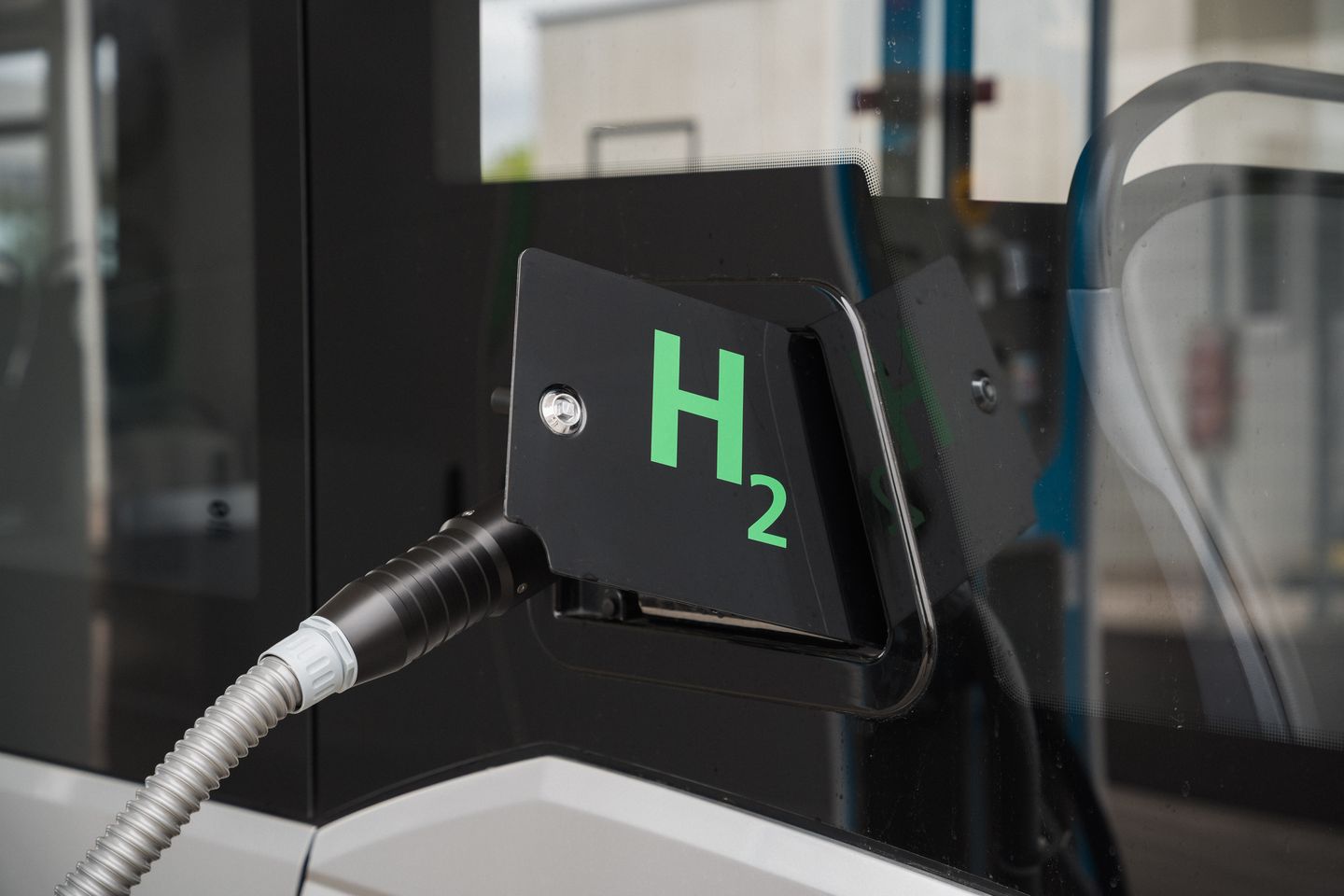 Zapfpistole mit H₂-Symbol betankt einen Brennstoffzellenbus an einer Wasserstofftankstelle. H2 MOBILITY