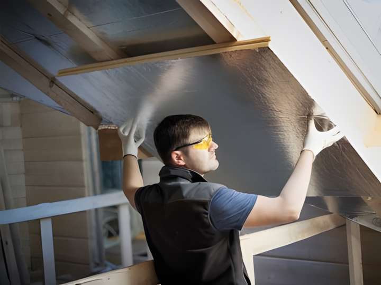 Ein Handwerker bringt Dämmplatten an einem Dach an