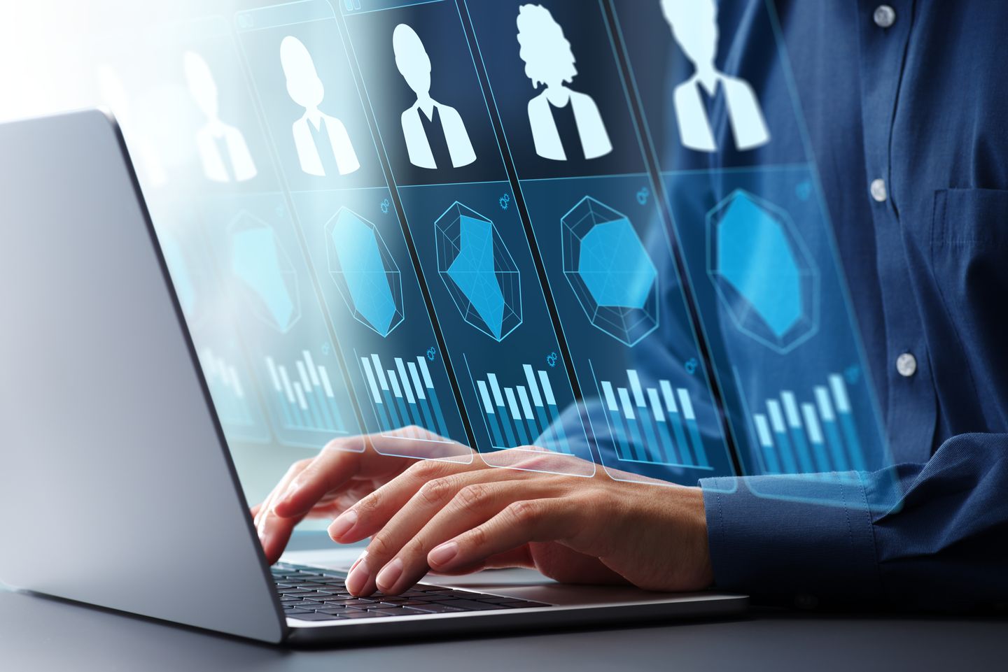 Person arbeitet an einem Laptop; darüber werden digitale Bewerberprofile und Auswertungen angezeigt © tadamichi via Getty Images