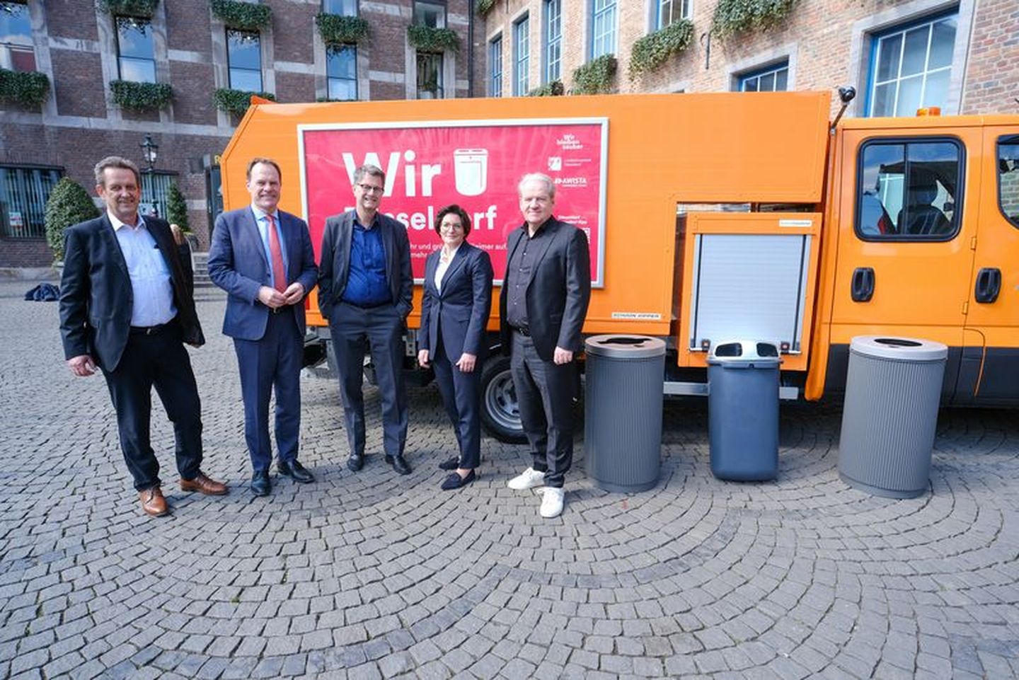 Beteiligte der Stadtsauberkeitsoffensive posieren als Gruppe vor einem Müllwagen und drei Mülleimern. © Gstettenbauer via duesseldorf.de