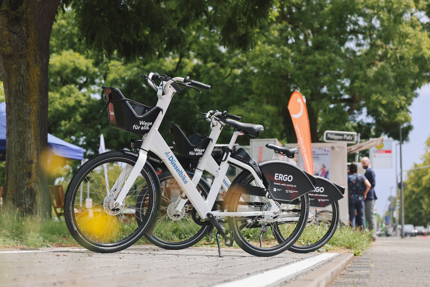 Mehrere weiße Düsselbikes mit Frontkörben stehen an einer gekennzeichneten Station in Düsseldorf © Daria Henken / Connected Mobility Düsseldorf GmbH (CMD)
